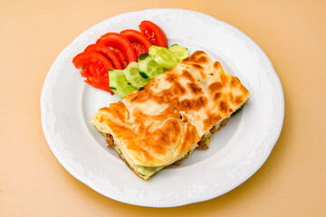 Turkish style meat stuffed filo dough borek served kol boregi. Cheese and minced pie are sliced on a marble background. Turkish name: Kol Boregi, kiymali, peynirli su boregi.