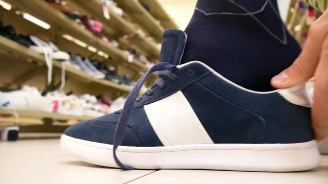 Close-up of a sport shoe in a shoe store and a man trying it on