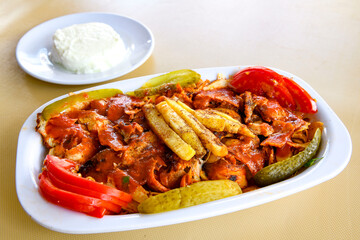 Turkish and Arabic Traditional Ramadan doner kebab with tasty tomato sauce and rice or turkish pilav in white plate on wood table background. ( Pilav ustu doner)