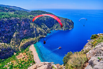 Landscape of flying paragliders over mountain and blue sea bay, Turkey - Powered by Adobe