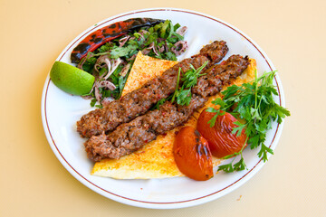 Grilled Turkish Adana, Urfa  Kebab with grilled vegetables, onion and rice on plate. Adana durum.
