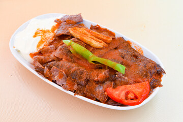 Turkish and Arabic Traditional Ramadan doner kebab with tasty tomato sauce and rice or turkish pilav in white plate on wood table background. ( Pilav ustu doner)