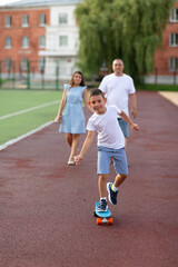 Fototapeta premium A boy learns to skate, his parents look at him from behind