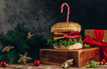 Christmas burger concept, with candy cane and christmas gift box. Dark background, Selective focus