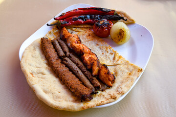 Grilled Turkish Adana, Urfa  Kebab with grilled vegetables, onion and rice on plate. Adana durum.