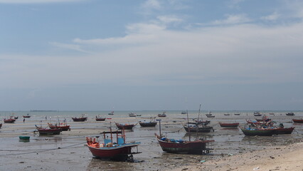 small fishing boat low tide, small boat out to sea with colored flags attached in the sea in Thailand. 