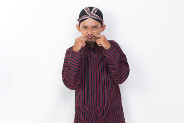 asian man with javanese traditional lurik cloth holding his nose because of a bad smelling isolated on white background