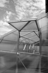 Polycarbonate greenhouse with iron frame elements of construction. Bearing frame, ventilation windows, transparent plastic fastening