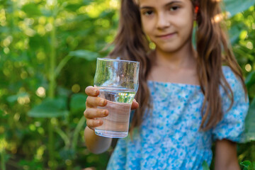 The child drinks water from a glass. Selective focus.