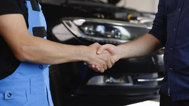 Automotive mechanic repairman handshake with client in garage. Vehicle service manager working in mechanics workshop. Success after check and maintenance car engine for customer. Car repair