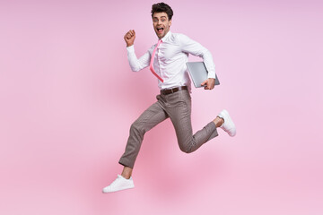Happy young man in shirt and tie jumping against pink background