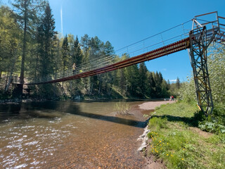 Man on a suspension bridge over a river in a natural park