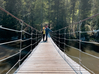 Fototapeta premium Man on a suspension bridge over a river in a natural park