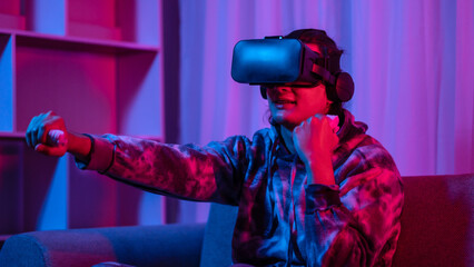 Young man wearing virtual reality (VR) glasses and uses joystick to play games with fun playing games in a room with red and blue lights, 3D game, Future games, Gadgets, Technology, Game concept