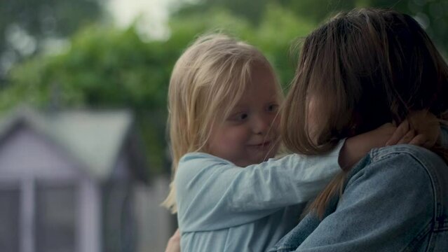 Mother and daughter hugging and looking fearfully at a thunderstorm with lightning. rainy summer day.