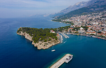 View of the harbor and city. Makarska riviera.Dolmatia.Blue south sea. Mountains, houses, yachts, ships, boats on the pier. City beach and pier. Drone footage. Summer. Adriatic. Relax. Vacation. 