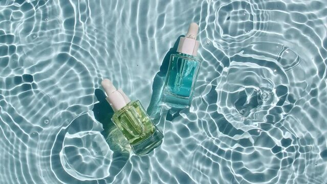 Cosmetic spa. Bottle for serum, micellar toner and emulsion on water texture background with splashes. Medical skin care. Video of packaging for design, advertising of a cosmetic product. 4k