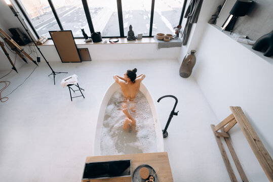 Relaxed lady taking bath, enjoying and relaxing while lying in bathtub, top view