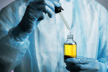 Gloved doctor hands  with pipette dropping liquid substance into transparent bottle,  clinical trials, analyzes and samples, cosmetology