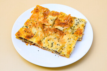 Turkish style meat stuffed filo dough borek served kol boregi. Cheese and minced pie are sliced on a marble background. Turkish name: Kol Boregi, kiymali, peynirli su boregi.