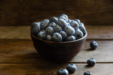Blueberries in a clay cup, on a wooden table. Ripe berries in the kitchen, harvest.