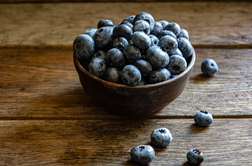 Blueberries in a clay cup, on a wooden table. Ripe berries in the kitchen, harvest.