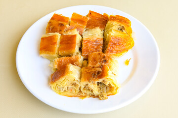 Turkish style meat stuffed filo dough borek served kol boregi. Cheese and minced pie are sliced on a marble background. Turkish name: Kol Boregi, kiymali, peynirli su boregi.
