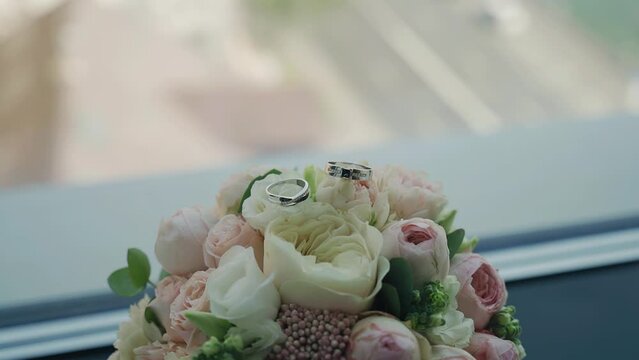 The camera takes a close-up of a bouquet of flowers with rings on top. Beautiful holiday objects