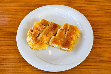 Turkish style meat stuffed filo dough borek served kol boregi. Cheese and minced pie are sliced on a marble background. Turkish name: Kol Boregi, kiymali, peynirli su boregi.