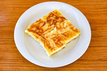 Turkish style meat stuffed filo dough borek served kol boregi. Cheese and minced pie are sliced on a marble background. Turkish name: Kol Boregi, kiymali, peynirli su boregi.