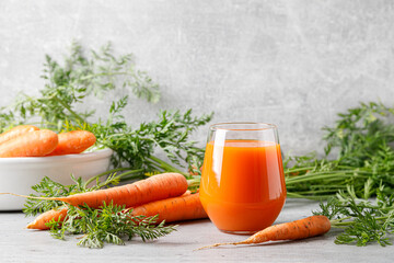 Carrot juice in a glass and fresh carrots with leaves - obrazy, fototapety, plakaty