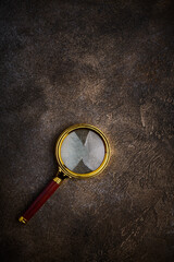 Magnifying glass with wooden handle on dark stone background