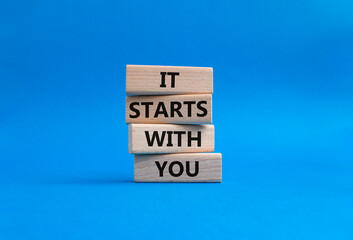 It starts with you symbol. Wooden blocks with words It starts with you. Beautiful blue background....