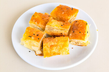 Turkish style meat stuffed filo dough borek served kol boregi. Cheese and minced pie are sliced on a marble background. Turkish name: Kol Boregi, kiymali, peynirli su boregi.