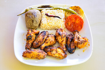 Chicken wings barbeque in a dish with BBQ sauce . Izgara tavuk sis kanat.