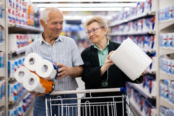 mature couple chooses paper towels in department of supermarket