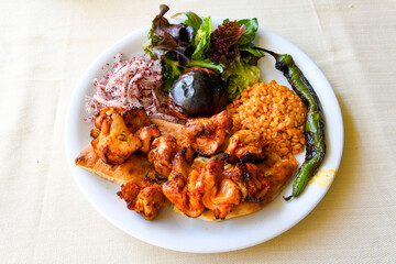Turkish and Arabic Traditional Ramadan doner kebab with tasty tomato sauce and rice or turkish pilav in white plate on wood table background. ( Pilav ustu doner)