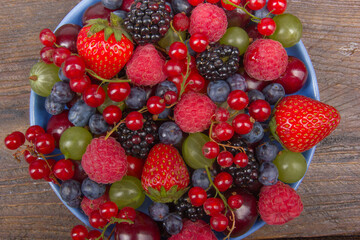 Fototapeta na wymiar Various summer Fresh berries in a bowl on rustic wooden table. Antioxidants, detox diet, organic fruits. Top view. Berries