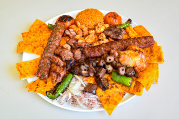 Grilled Turkish Adana, Urfa  Kebab with grilled vegetables, onion and rice on plate. Adana durum .