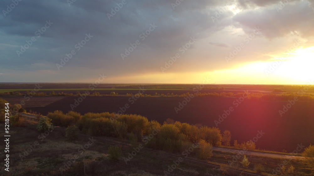 Poster sunset, clouds and fields from a height in summer.