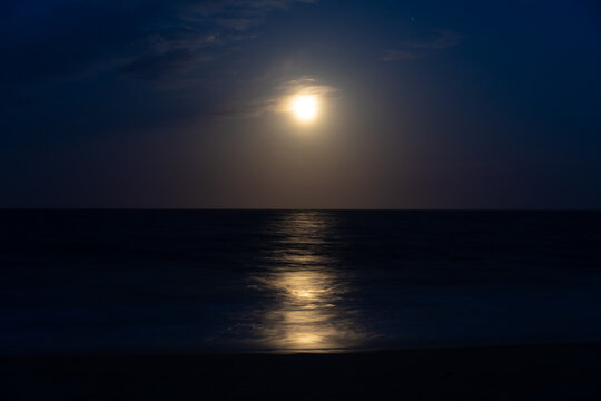 Beach at night with moon in sky