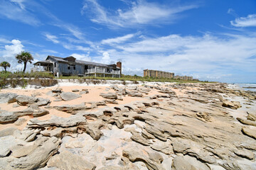 Old vacant house on the beach with beachfront condo with coquina rock beach in Palm Coast, Florida between St Augustine and Flagler Beach. 