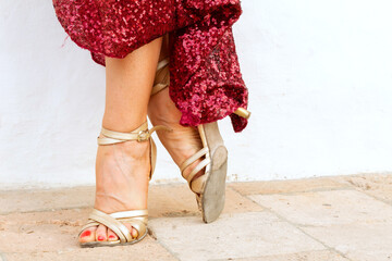 feet of tango dancer woman posing with red dress in home garden dancing outdoors in the city
