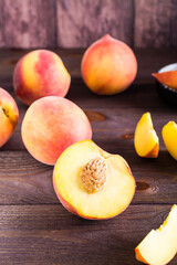 Fresh peaches sliced and whole on a wooden table. Organic vitamin food. Vertical view