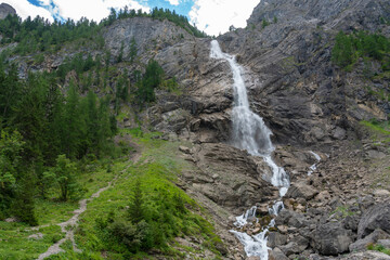 Wasserfall im Tal von Adelboden, weithin sichtbar über den Bäumen. Engstligenfälle am Talende....