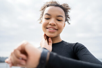 Uses the fitness watch app on her arm, a female athlete is running, doing an active workout outside