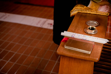 A close-up of religious artifacts on a wooden surface, including a candle and metal bowl.