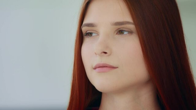 Close up caucasian lonely thoughtful woman redhead young 20s girl with long straight hair looking at distance deep in thoughts pondering new idea feel calmness melancholic mood expressing sad emotion