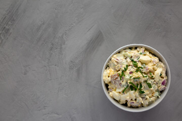 Homemade Healthy Potato Salad with Eggs in a Bowl on a gray surface, top view. Flat lay, overhead, from above.