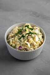 Homemade Healthy Potato Salad with Eggs in a Bowl on a gray background, side view.
